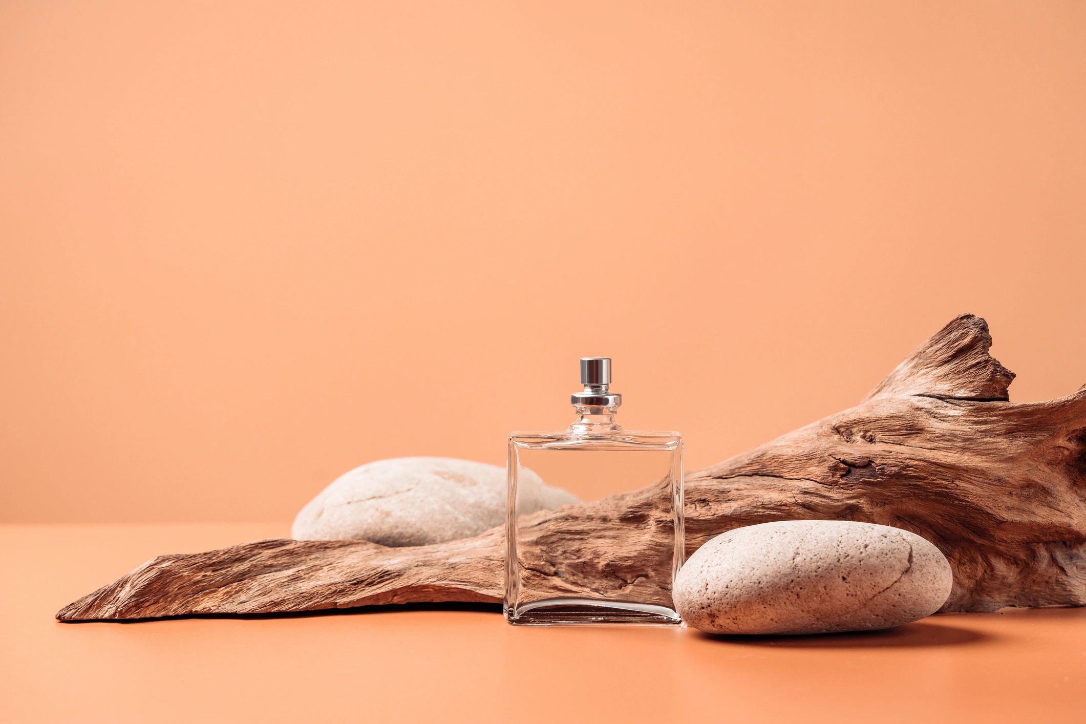 Botella de perfume con estética amaderada sobre fondo rústico con espacio para texto